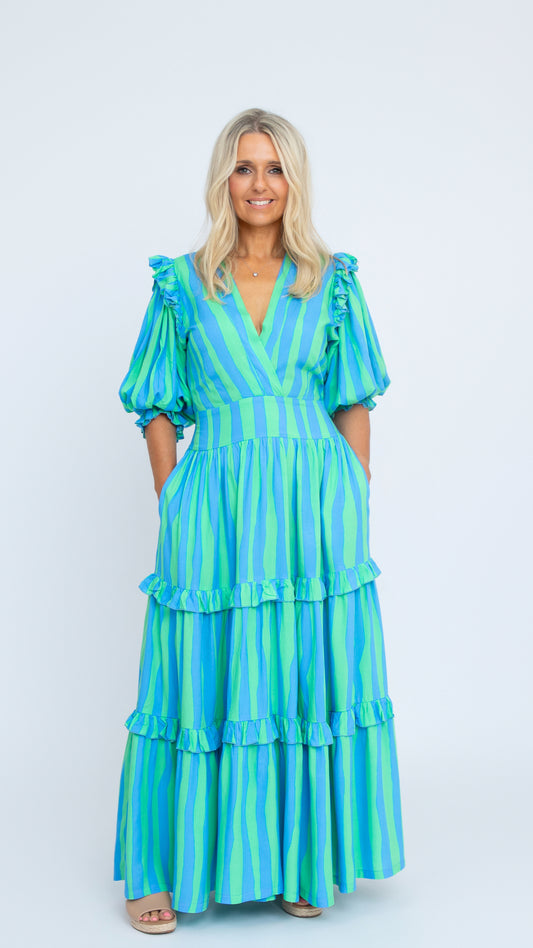 The Amy Dress in blue and green striped rayon with V-neck and puff sleeves, full-length tiered skirt. By Nancy The Label.